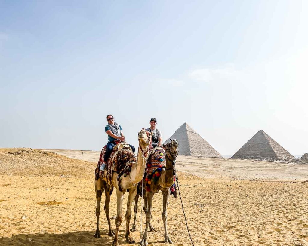 people on camels in front of giza pyramids